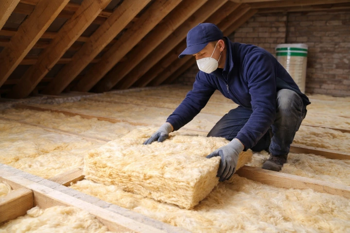 Artisan posant un isolant dans des combles